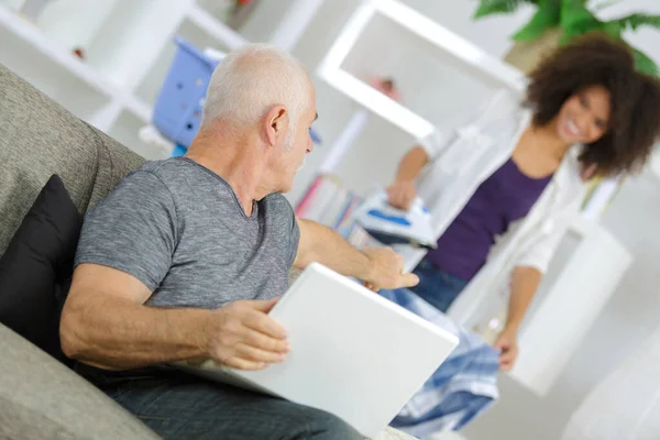 Velho homem usando laptop enquanto conversa com seu assistente — Fotografia de Stock