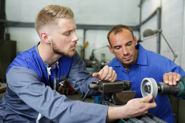 Two male engineers working together on machinery — Stock Photo, Image