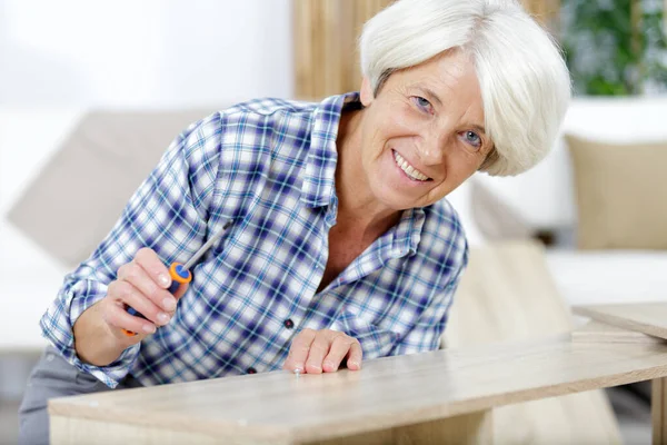 Senioren vrouw repareren van een meubilair — Stockfoto