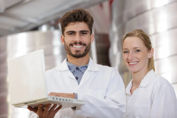 Voedselverwerkende werknemers poseren met laptop — Stockfoto