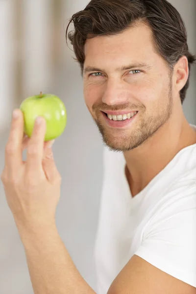 녹색 사과를 들고 미소짓고 있는 젊은 남자 — 스톡 사진