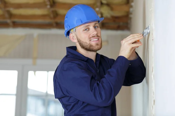 Man peeling wall with plaster spatula — Stock Photo, Image