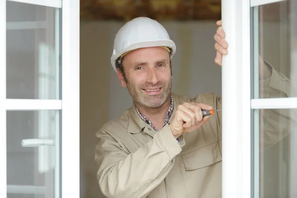 Trabalhador da construção que instala a janela na casa — Fotografia de Stock