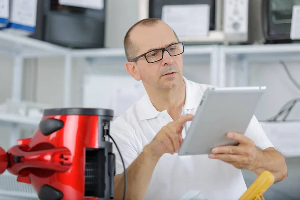 Man met elektrische apparaten op zoek naar tablet — Stockfoto