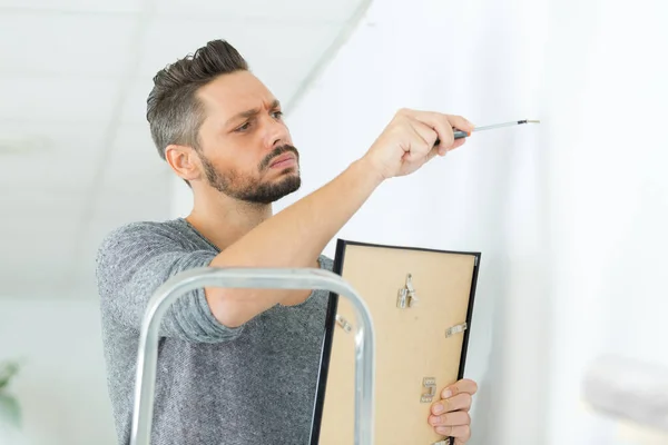 Man die een frame op de muur monteert — Stockfoto