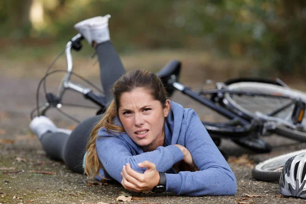 Jovem mulher caiu de bicicleta e segurando seu cotovelo — Fotografia de Stock