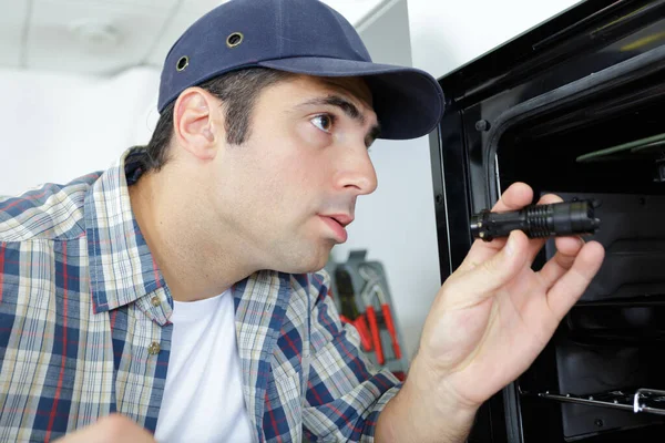 Male electrician checking an oven — Stock Photo, Image