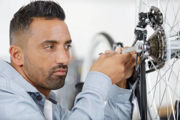 Un hombre reparando una rueda de bicicleta —  Fotos de Stock