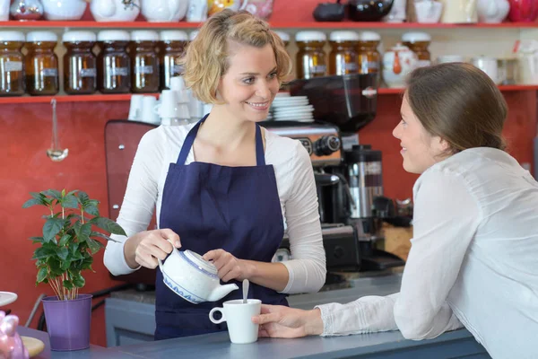 Camarera sirviendo una taza de café al cliente en la cafetería — Foto de Stock