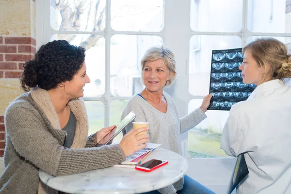 Female doctor and patient holding the mri film image — Stockfoto