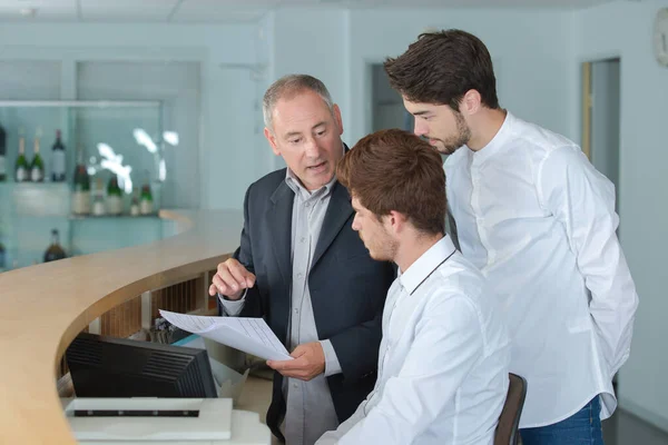 Young men being trained at reception desk — Stockfoto