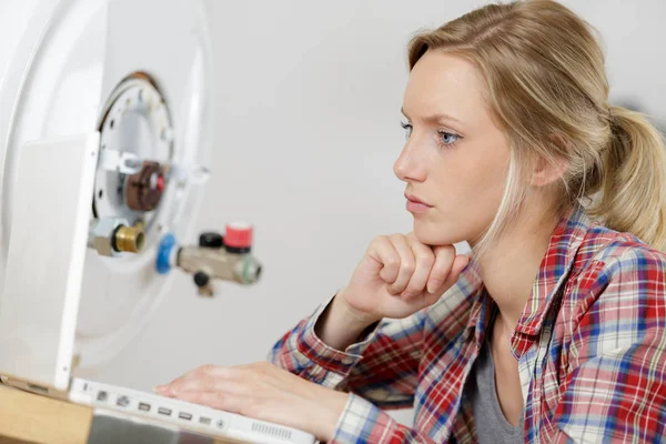 Vrouwelijke loodgieter onderzoeken ketel probleem in laptop — Stockfoto