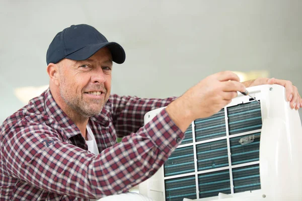 Male technician repairing air conditioner outdoors — Stock Photo, Image