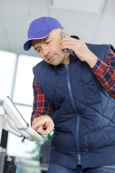 Man aan de telefoon die een kantoorprinter repareert — Stockfoto