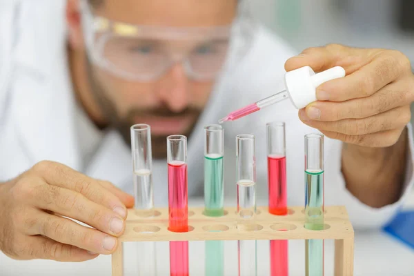 Lab technician filling test tubes with chemical liquids — Stock Photo, Image