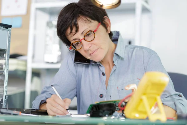 Vrouw aan de telefoon met mannelijke klant testen van een moederbord — Stockfoto