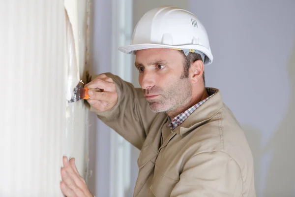 Ein Mann entfernt die Tapete — Stockfoto