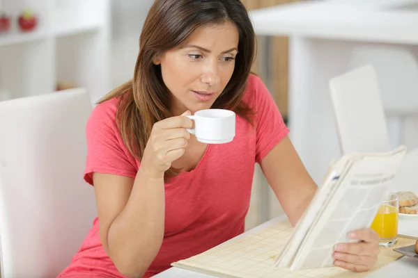 Donna a casa a bere caffè durante la lettura del giornale — Foto Stock