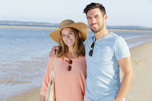 Uśmiechnięta para trzymająca się za ręce na plaży — Zdjęcie stockowe