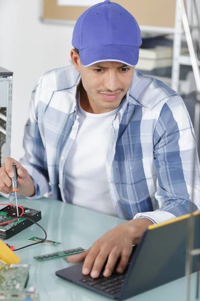 Homem usando um laptop para corrigir um PC — Fotografia de Stock