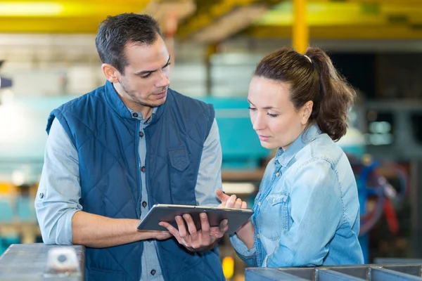 Mann und Frau prüfen Tablette in Fabrik — Stockfoto