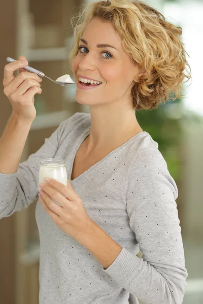 Молодая женщина с йогуртом в помещении — стоковое фото