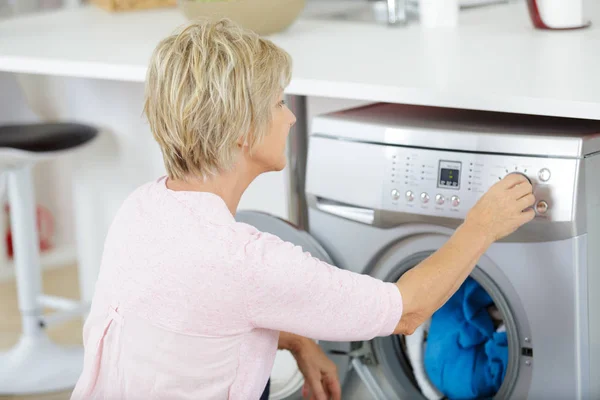 Une femme mature utilisant une machine à laver — Photo