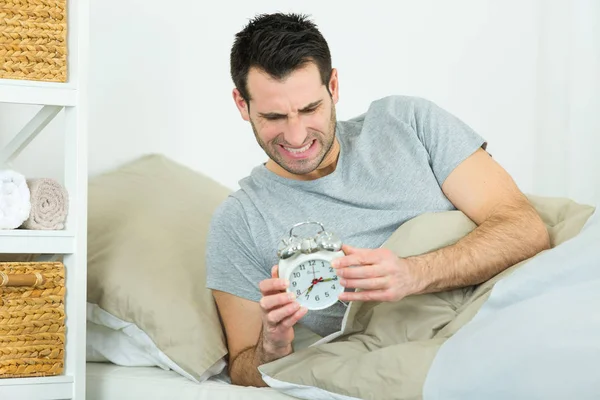 Triste hombre infeliz tratando de llegar al despertador — Foto de Stock