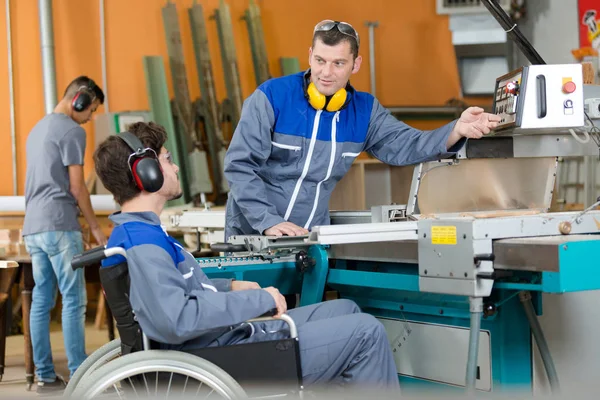 Инвалид в инвалидной коляске на заводе на станке — стоковое фото