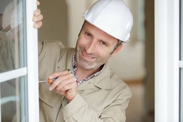 Happy male builder fixing a window — Stock Photo, Image