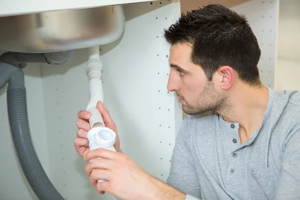 Man fixing pipes under the sink — Stock Photo, Image