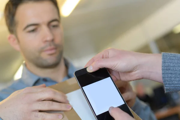 Hombre entrega madura escaneo caja de cartón con teléfono inteligente — Foto de Stock