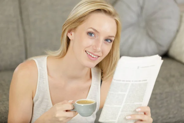 젊은 여자는 소파에 앉아 신문을 읽고 — 스톡 사진
