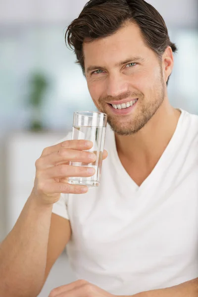 Glücklicher Mann, der zu Hause Wasser trinkt — Stockfoto