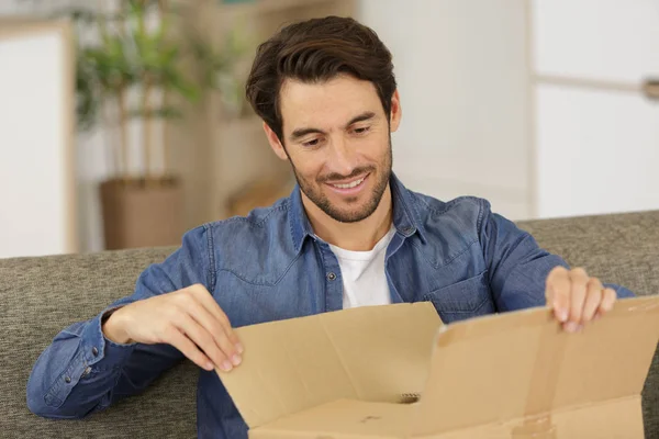 Glad man öppna paket låda hemma — Stockfoto