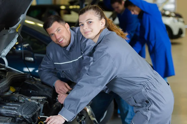 Jonge vrouwelijke stagiair tot vaststelling van automotoren in garage — Stockfoto