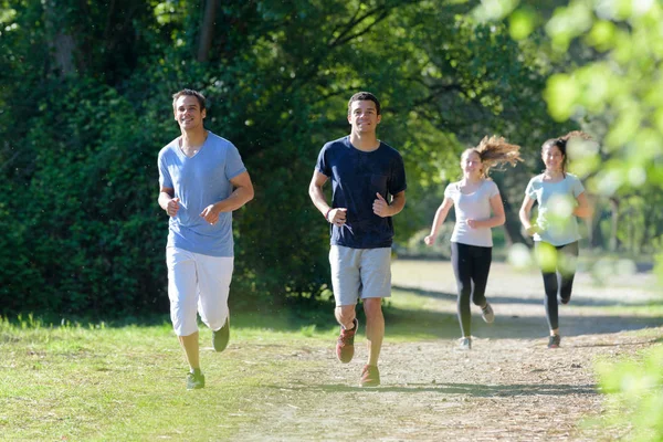 Dos hombres y dos mujeres corriendo en el parque — Foto de Stock
