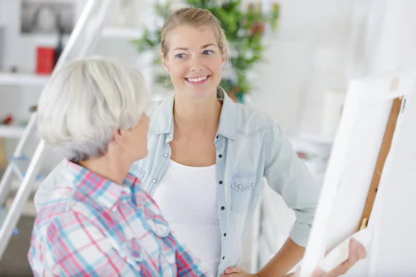 Elderly lady showing picture to young woman — Stock Photo, Image