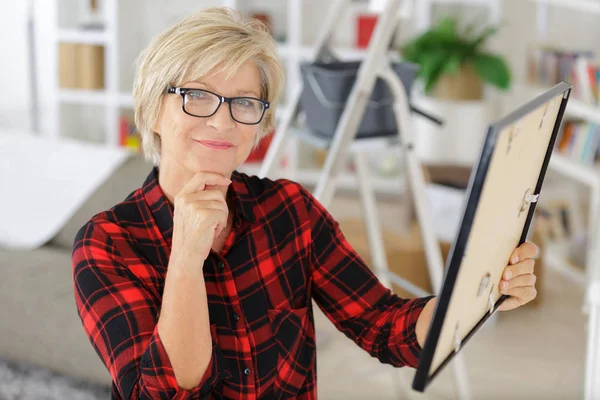 Mujer contemplativa sosteniendo marco de imagen — Foto de Stock