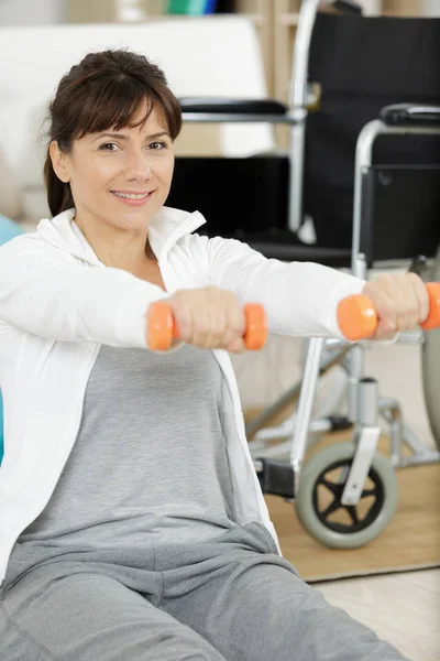 Mujer en silla de ruedas levantamiento mancuernas — Foto de Stock