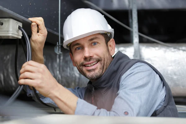 Electrician installing cables in roof — Stock Photo, Image