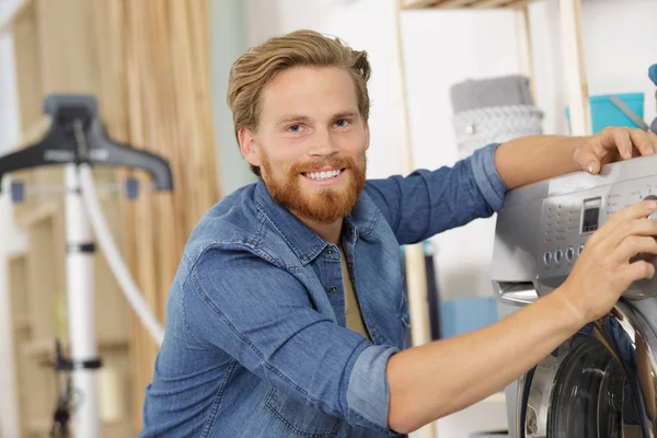 Щасливий чоловік робить пральну машину — стокове фото