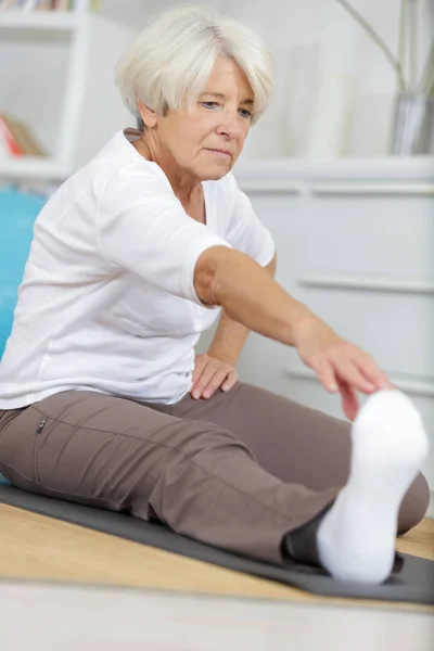 Donna anziana allungando le gambe — Foto Stock