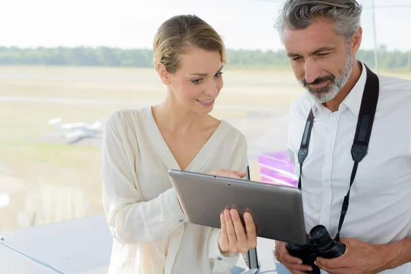 Man en vrouw staan met tablet en praten in hangar — Stockfoto