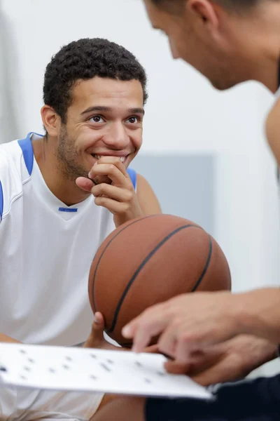 Basketspelare skrattar medan tränaren pratar — Stockfoto