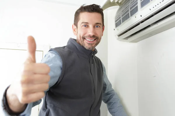 Le Man Elektriker Gesturing tummar upp nära luftkonditionering — Stockfoto