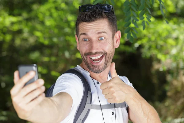 Szczęśliwy człowiek robi selfie pokazując kciuk w górę — Zdjęcie stockowe