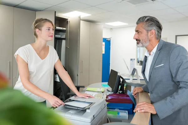Recepcionista hablando con el cliente mientras hace fotocopias — Foto de Stock