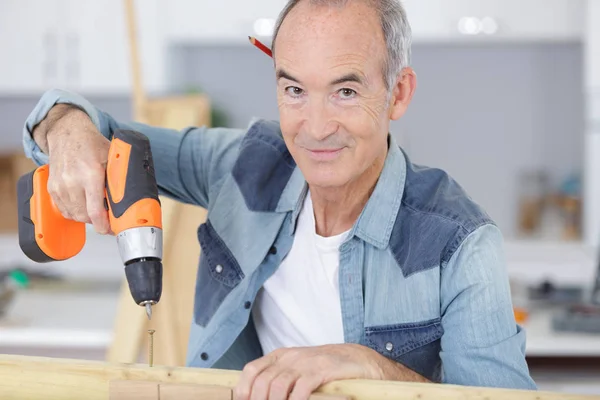 Muž vrtání dřeva doma — Stock fotografie