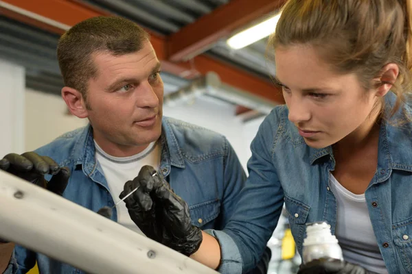 Meccanico auto guida una tirocinante donna in garage — Foto Stock